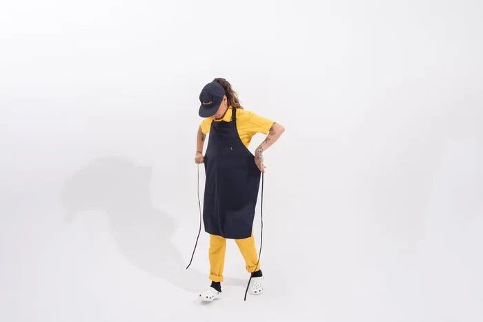 Person wearing a navy blue apron and yellow pants on a white background